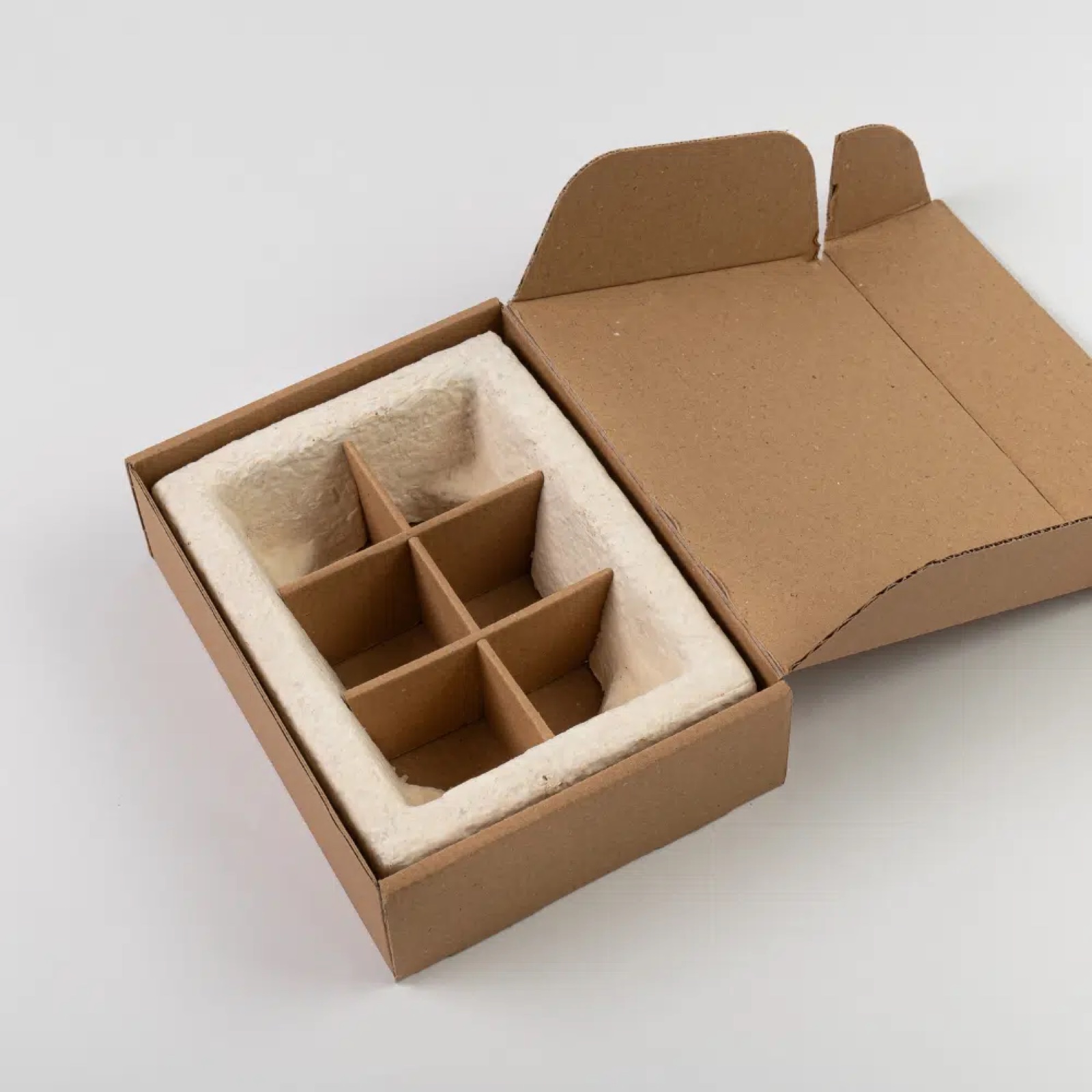 Six-cavity molded mycelium insert seated inside a kraft carton, engineered cushioning